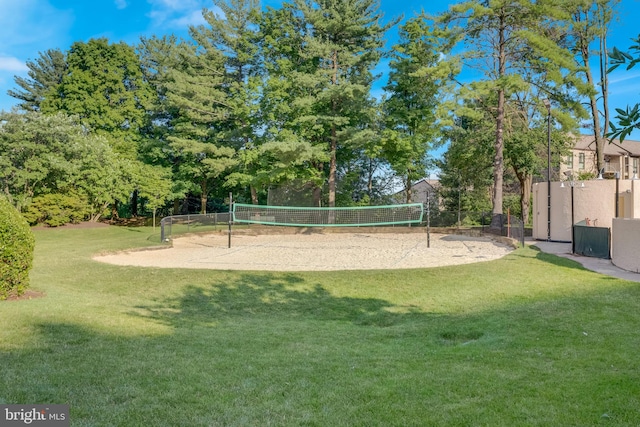 view of property's community featuring a yard, volleyball court, and fence