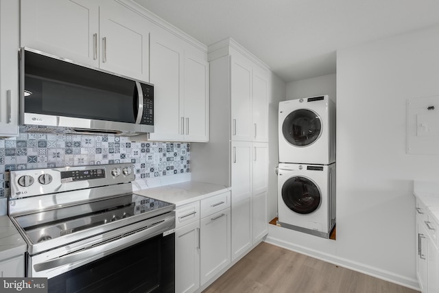 kitchen with stainless steel appliances, backsplash, light wood-style floors, white cabinetry, and stacked washing maching and dryer