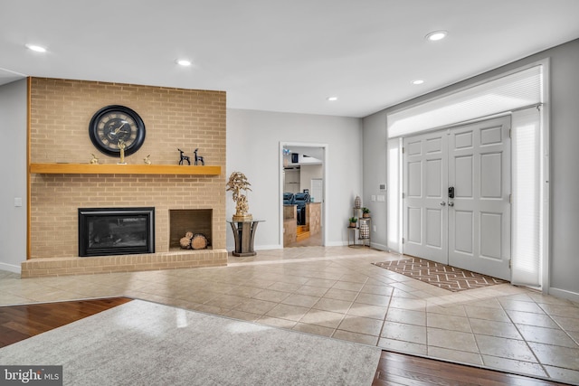 foyer with recessed lighting, a brick fireplace, baseboards, and tile patterned floors