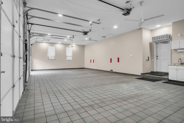 garage with a garage door opener, a sink, ceiling fan, and baseboards