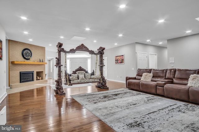 living room with baseboards, wood-type flooring, a fireplace, and recessed lighting