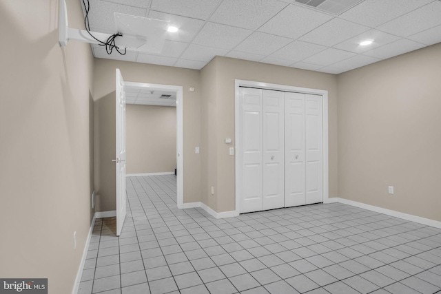 unfurnished bedroom featuring light tile patterned floors, baseboards, visible vents, a paneled ceiling, and a closet