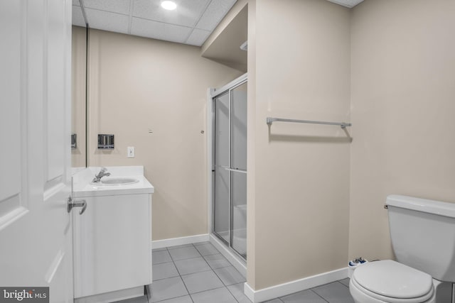 bathroom with a paneled ceiling, a shower stall, toilet, and tile patterned floors