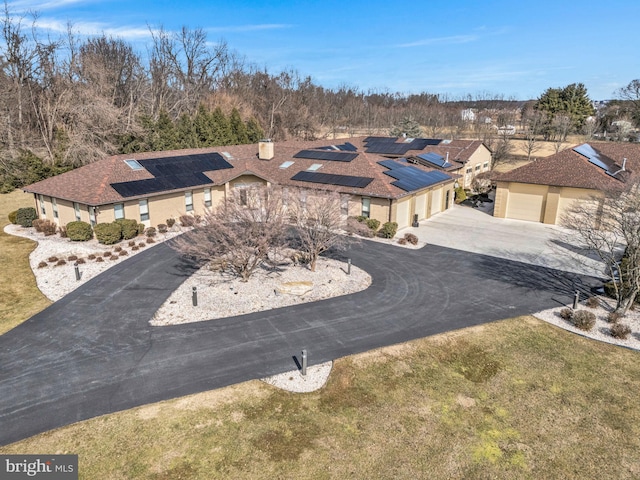 view of front of house featuring driveway, an attached garage, a front lawn, and solar panels