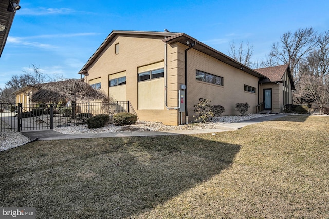 view of side of home with fence, a lawn, and brick siding