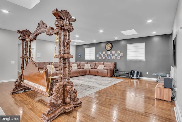 living area featuring a skylight, hardwood / wood-style floors, and recessed lighting