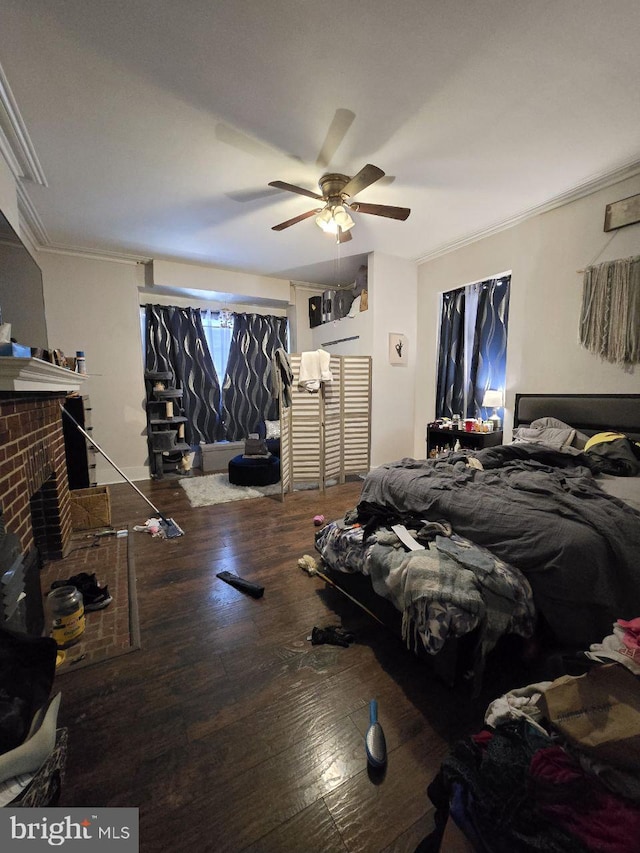 bedroom with ornamental molding, a brick fireplace, ceiling fan, and wood finished floors