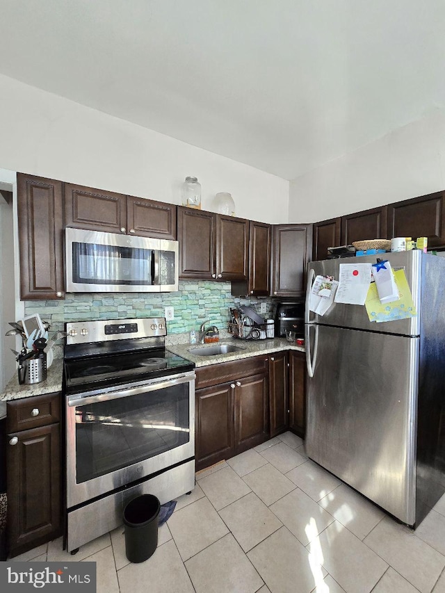 kitchen featuring appliances with stainless steel finishes, backsplash, a sink, and dark brown cabinetry