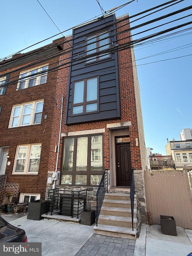 townhome / multi-family property featuring brick siding and fence