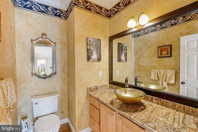 half bathroom featuring toilet, vanity, and baseboards