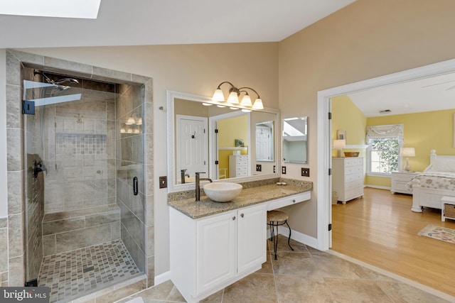 bathroom featuring baseboards, lofted ceiling with skylight, a stall shower, wood finished floors, and vanity