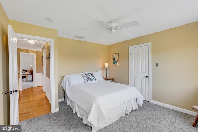 carpeted bedroom with visible vents, baseboards, and a ceiling fan