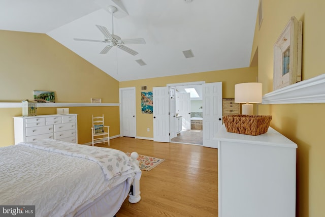 bedroom with ensuite bathroom, lofted ceiling, wood finished floors, and a ceiling fan