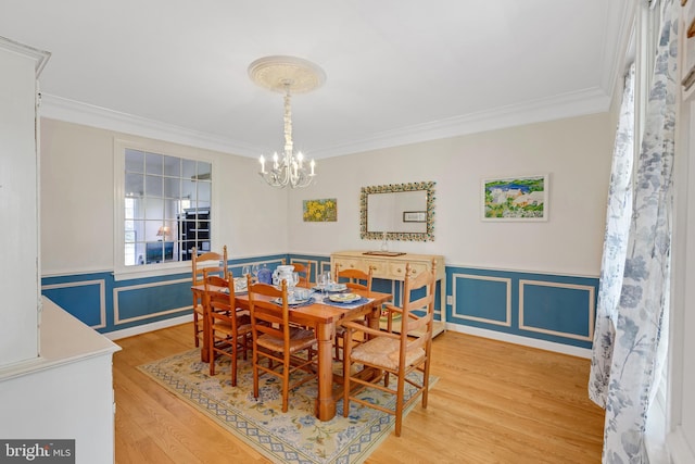 dining area with a notable chandelier, wood finished floors, wainscoting, and ornamental molding