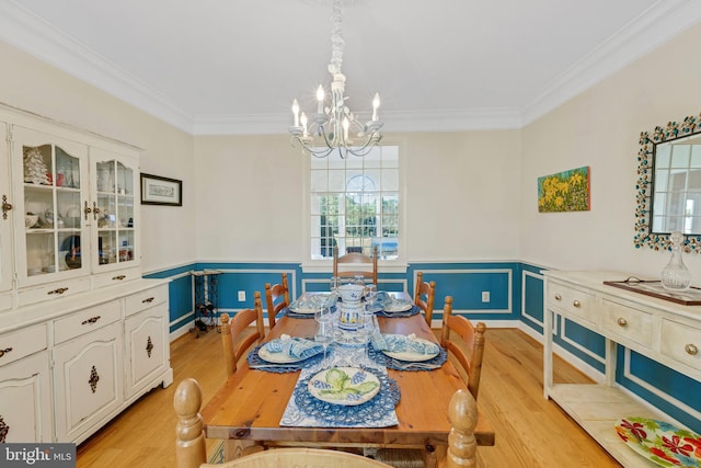 dining room with an inviting chandelier, crown molding, light wood-type flooring, and wainscoting