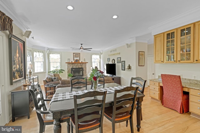 dining area with built in desk, a ceiling fan, light wood-style floors, and ornamental molding