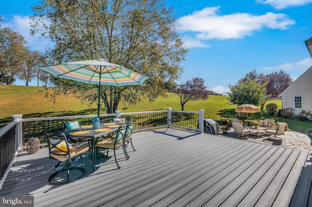 deck featuring outdoor dining space and a lawn