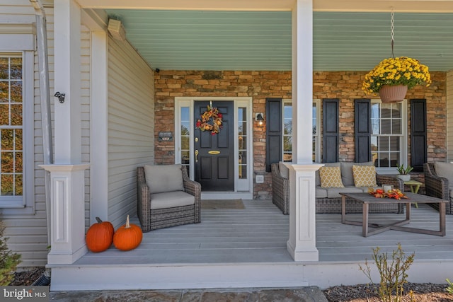 view of exterior entry with stone siding and a porch