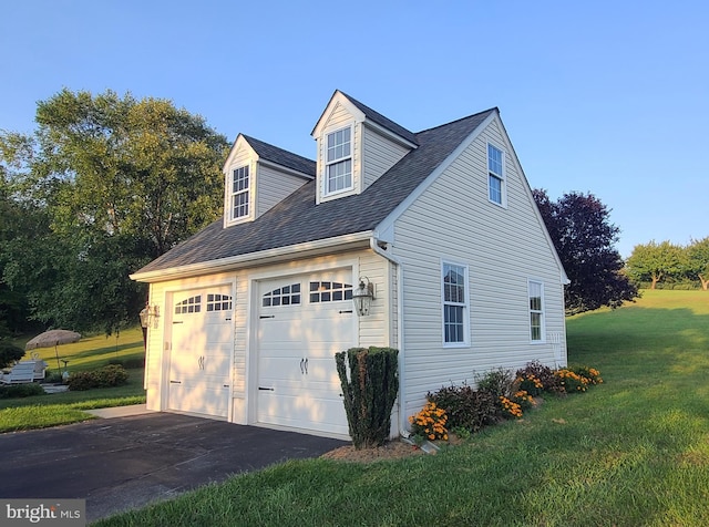 view of side of property featuring aphalt driveway, a lawn, and an attached garage