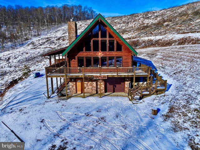 snow covered property with a chimney, stone siding, stairway, and log siding