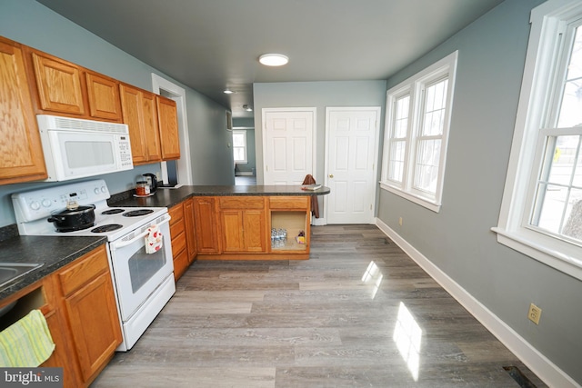 kitchen with dark countertops, white appliances, a healthy amount of sunlight, and baseboards