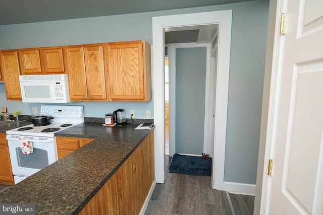 kitchen featuring brown cabinets, white appliances, dark wood finished floors, and baseboards