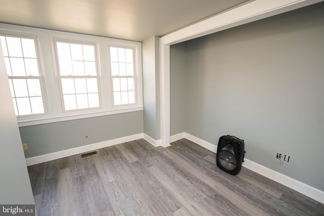 unfurnished room with dark wood-style floors, visible vents, and baseboards