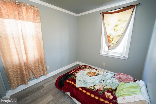 bedroom with ornamental molding, wood finished floors, and baseboards