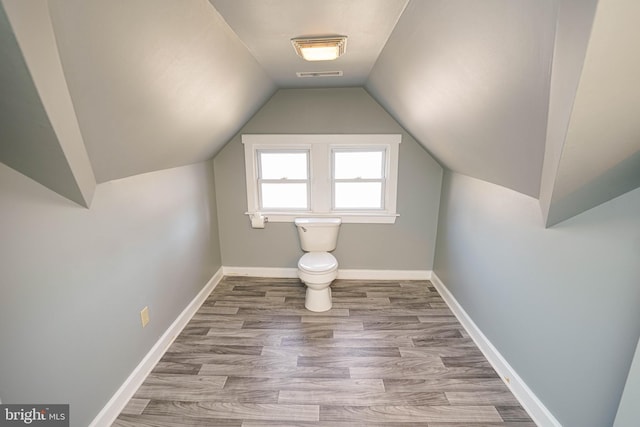 bonus room with lofted ceiling, visible vents, baseboards, and wood finished floors