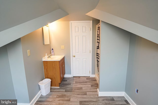 bonus room featuring light wood-type flooring, a sink, and baseboards