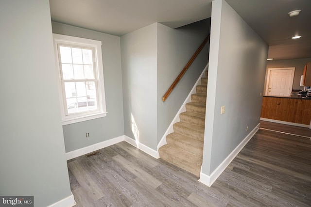 stairway featuring visible vents, baseboards, and wood finished floors