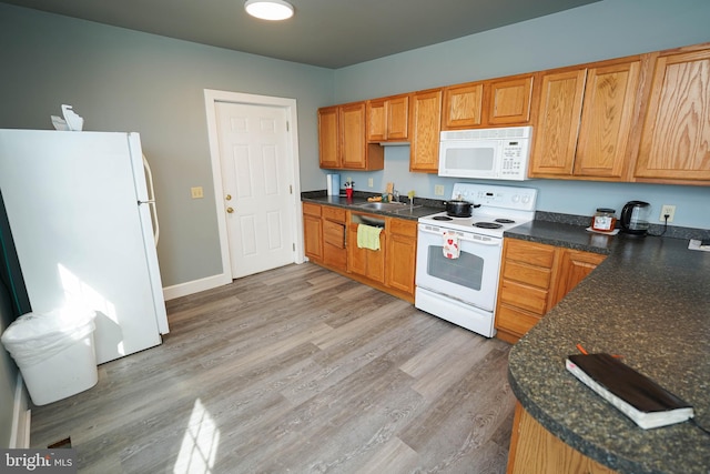 kitchen with dark countertops, white appliances, and light wood-style floors