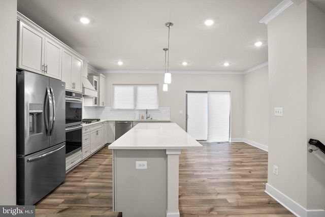 kitchen featuring stainless steel appliances, ornamental molding, decorative backsplash, and a kitchen island