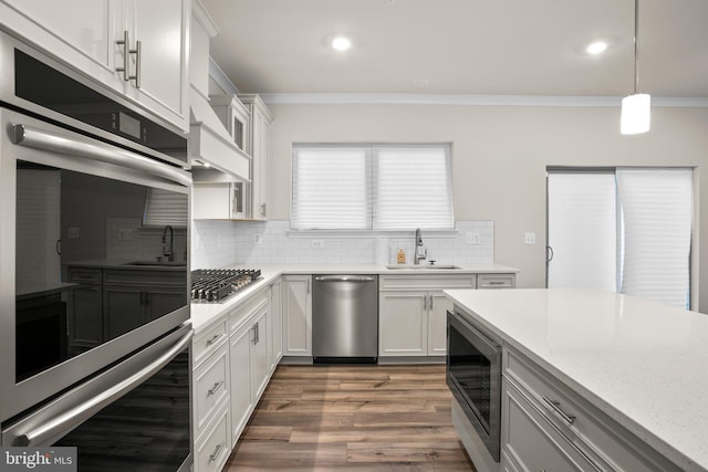 kitchen featuring stainless steel appliances, crown molding, backsplash, and a sink