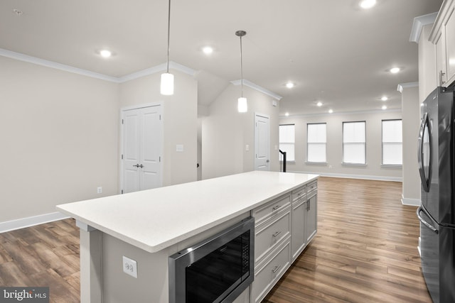 kitchen featuring built in microwave, light countertops, crown molding, and freestanding refrigerator