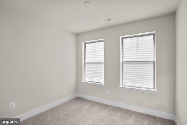 spare room featuring light carpet, baseboards, and visible vents