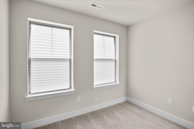 unfurnished room featuring carpet, visible vents, and baseboards