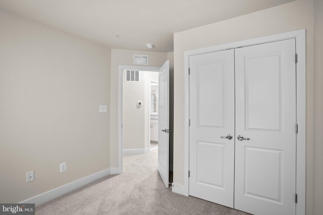 unfurnished bedroom with light carpet, baseboards, visible vents, and a closet