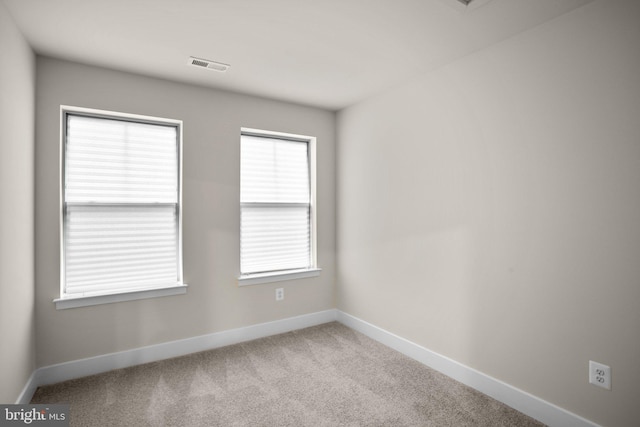 carpeted empty room featuring visible vents and baseboards