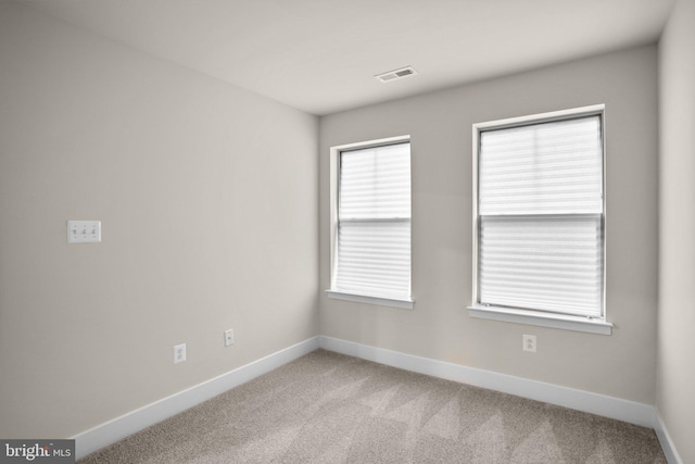 carpeted spare room featuring visible vents and baseboards