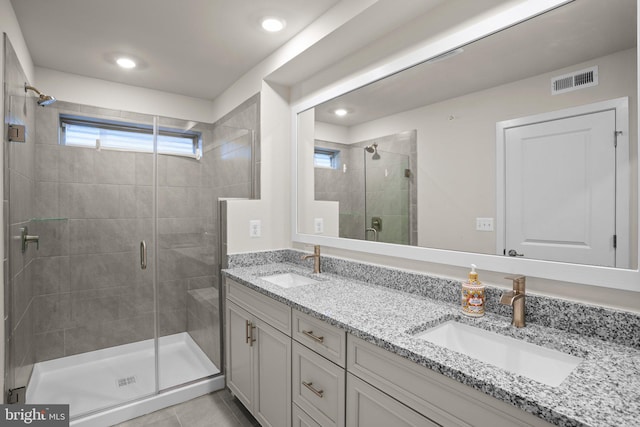 full bath with double vanity, a shower stall, visible vents, and a sink