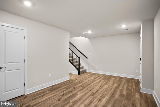 below grade area featuring baseboards, visible vents, stairway, wood finished floors, and recessed lighting