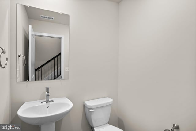 bathroom with toilet, visible vents, and a sink