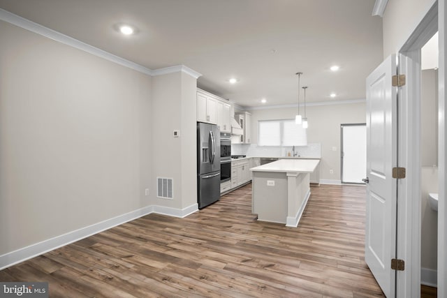 kitchen with visible vents, light countertops, appliances with stainless steel finishes, dark wood finished floors, and crown molding