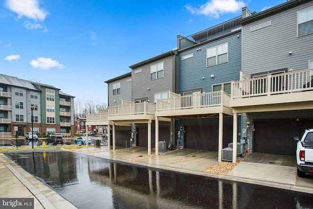 back of property with a garage, driveway, and central AC unit