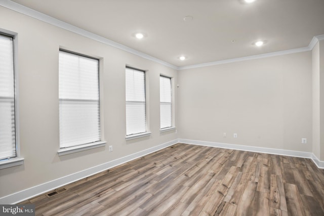 spare room with ornamental molding, visible vents, baseboards, and wood finished floors