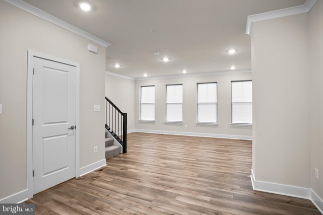 spare room featuring stairs, baseboards, wood finished floors, and crown molding