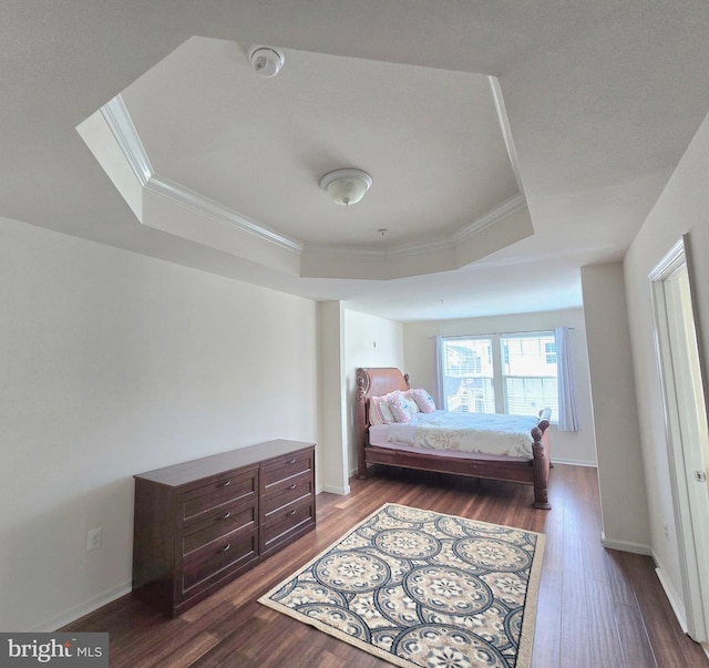 bedroom with dark wood-style flooring, a raised ceiling, and crown molding