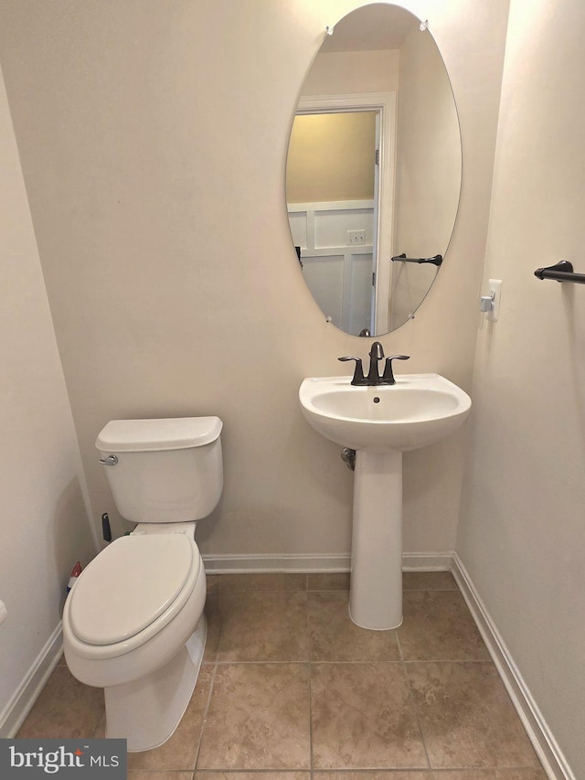 half bathroom with tile patterned flooring, toilet, and baseboards