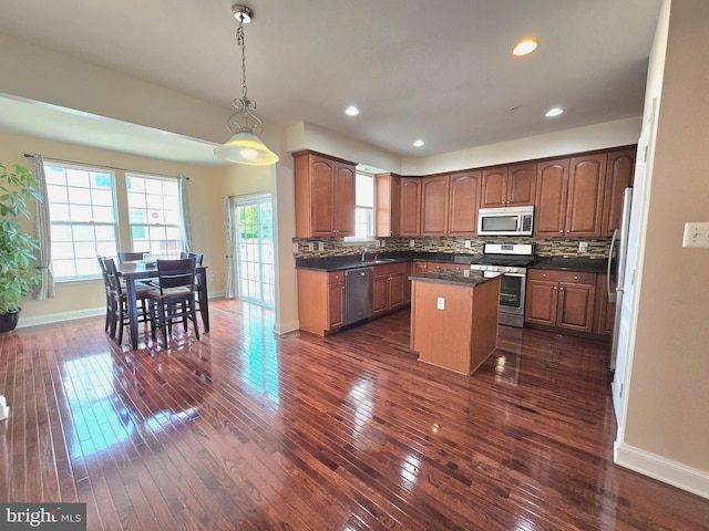 kitchen with stainless steel appliances, dark countertops, a kitchen island, and decorative backsplash